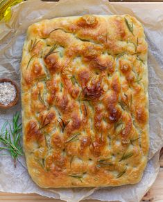 a square bread with herbs on it and some dipping sauces next to the bread