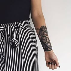 a person with a tattoo on their arm holding a cell phone and wearing striped pants