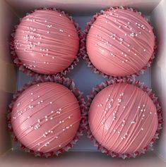 four pink cupcakes with white sprinkles in a box