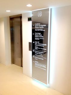 an elevator with glass doors and signs on the wall in a room that has white walls