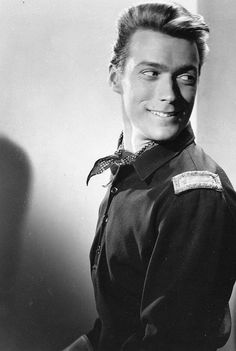 black and white photograph of a man in uniform smiling at the camera with his hands on his hips