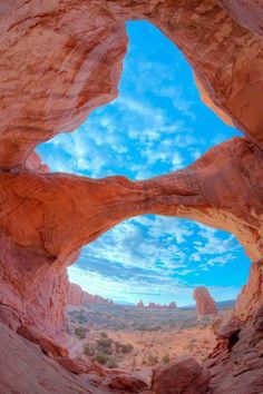 the view from inside an arch in a rock formation with blue sky and clouds above