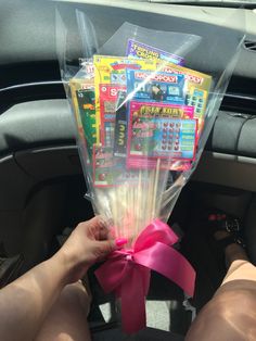 someone is holding up some candy sticks in the back seat of a car with pink ribbon