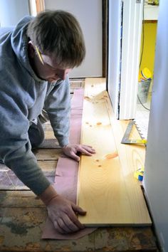 a man is working on some wood in his house, while he looks down at the floor