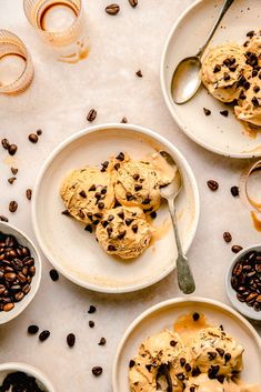 two white plates topped with cookies and chocolate chips next to bowls of coffee beans on a table