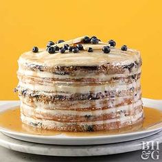 a cake with frosting and blueberries sitting on a plate