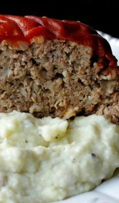 meatloaf with mashed potatoes and ketchup on a white plate, ready to be eaten