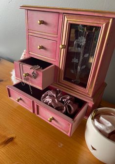 a pink jewelry box sitting on top of a wooden table