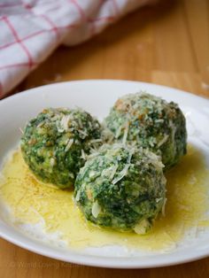 three balls of broccoli covered in cheese and parmesan on a white plate