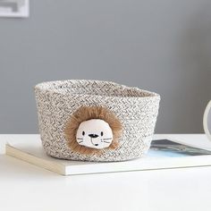 a small basket with a lion face on the side and a coffee cup next to it