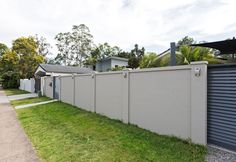 a fenced in yard next to a house with garage doors on both sides and green grass