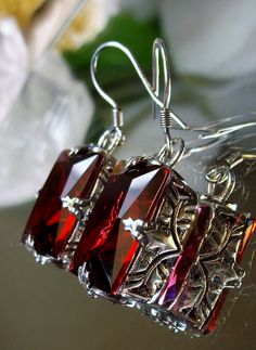 Earrings Description Made to Order This is a brand new beautiful Art Nouveau/Art Deco-inspired filigree sterling silver pair of earrings. The gorgeous 16ctw Simulated Red Ruby are 16mm (5/8th of an inch) by 12mm (1/2 inch) in size dimension. The earrings are marked 925. The earrings are 1 5/16th inches long. Notice the beautiful swirl/heart like craftsmanship of the silver filigree settings. This is a well made beautiful pair of sterling earrings and they are ready to wear. A white gift-box is i Formal Rectangular Garnet Jewelry, Red Rectangular Sterling Silver Jewelry, Ruby Filigree Jewelry Gift, Ruby Filigree Jewelry As A Gift, Rectangular Red Sterling Silver Jewelry, Red Metal Filigree Jewelry, Rectangular Silver Ruby Jewelry, Rectangular Ruby Jewelry In Silver, Red Filigree Dangle Jewelry