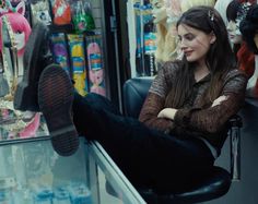 a woman is sitting on a chair in front of a store window with her legs crossed