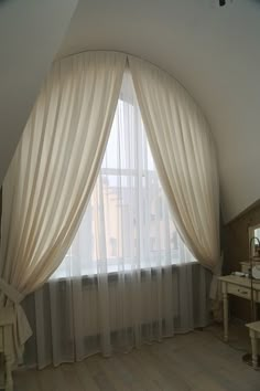 a bedroom with a large window and white curtains