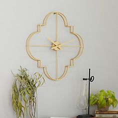 a clock that is on the wall next to a potted plant and some books