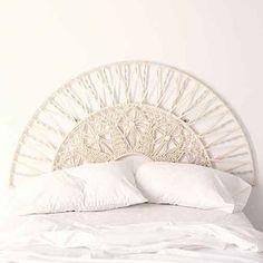 a white bed topped with pillows next to a wall mounted headboard in a bedroom