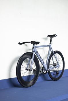 a bicycle is shown against a white wall with blue flooring in the foreground