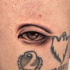 a close up of a person's leg with an eye and ghost tattoos on it