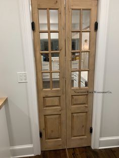 two wooden doors with glass panels in a home entryway, next to a hardwood floor