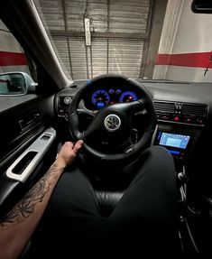 a man driving a car in the dark with his hands on the steering wheel and dashboard