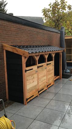 an outdoor storage shed with wooden doors and roof