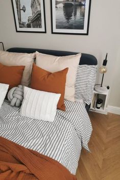 a bed with two pictures on the wall above it and an orange striped comforter