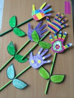 handprinted flowers and leaves on a table with colored pencils next to them