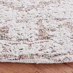 an area rug with white and brown colors on the floor, closeup view from above