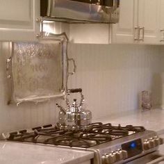 a stove top oven sitting inside of a kitchen next to white cupboards and drawers