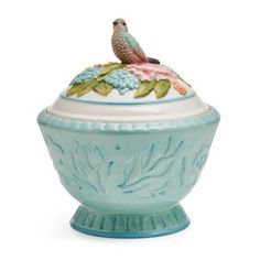 a blue and white vase with a bird sitting on it's top, in front of a white background