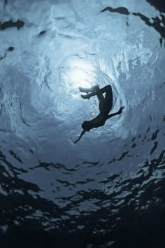 a person swimming in the water with their back turned to the camera and looking up