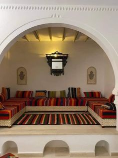 a living room with couches and rugs on the floor in front of an archway