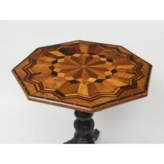 a wooden table with an intricate design on it's top and base, sitting against a white background