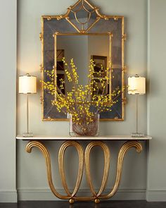 a vase with yellow flowers sitting on top of a table in front of a mirror