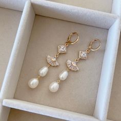 a pair of earrings in a box with pearls and crystals on it, sitting inside