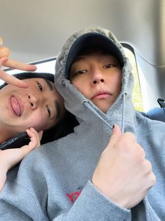 two people in grey hoodies posing for the camera with one pointing at the camera