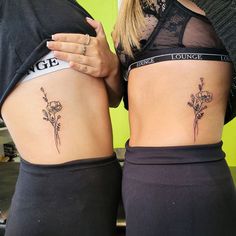 two women with tattoos on their stomachs, one has a flower and the other has a name