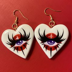 two heart shaped earrings with an eye painted on them