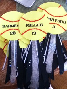 three yellow softballs with black and silver ribbons