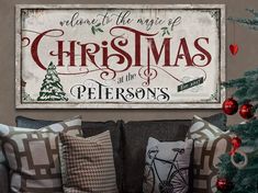 a christmas sign is hanging on the wall above a couch with pillows and throw pillows