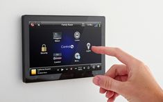 a person pointing at a touch screen on a wall mounted device with buttons and icons