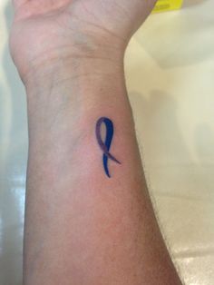 a blue ribbon tattoo on the wrist