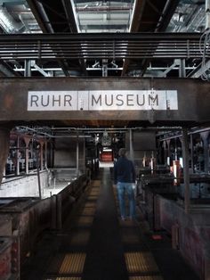 a man walking down a long hallway in an industrial building