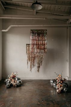 two vases filled with flowers sitting in front of a wall hanging from the ceiling