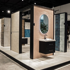 a bathroom area with sink, mirror and shower stall in the middle of floor to ceiling tiles