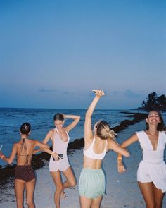 four young women are dancing on the beach