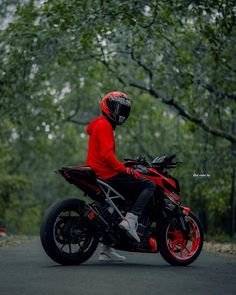 a person wearing a helmet is sitting on a red and black motorcycle in the street