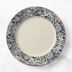 an ornate blue and white plate with gold trimmings on it, sitting on a marble surface