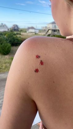 the back of a woman's shoulder with small red flowers on her left arm