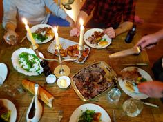 people sitting at a table with plates of food and candles in front of them,